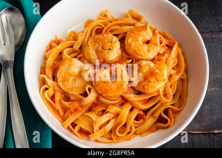 Schüsseln mit Garnelen und Pasta in Tomatensahnesauce: Schüsseln mit Garnelen und Fettuccine Nudeln in einer cremigen Tomatensoße Stockfoto