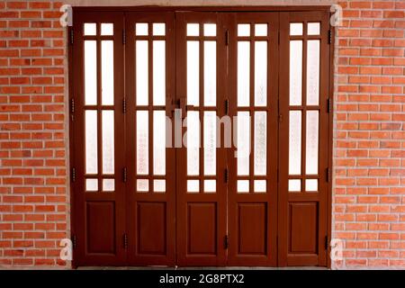 Wandziegel Moderne und Akkordeontüren Holz und gemustertes Glas mit dem alten Holzschloss. Stockfoto