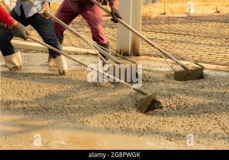 Drei Bauarbeiter nivellieren Betonpflaster. Stockfoto