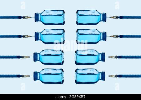 Einige Impfstofffläschchen mit einer blauen Flüssigkeit und einige Spritzen klebten darauf, die in verschiedenen Linien auf einem hellblauen Hintergrund angeordnet sind Stockfoto