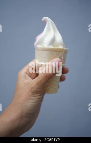 Hand hält Softeis in Waffel mit grauem Hintergrund Stockfoto
