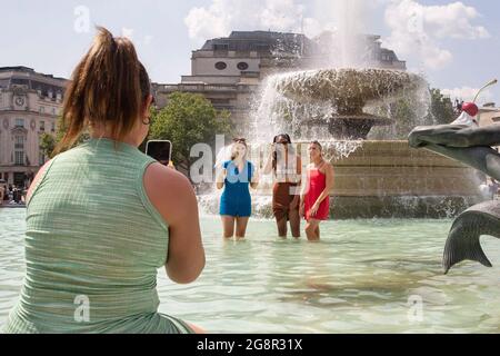 Während einer Hitzewelle im Juli 2021 stehen Menschen in den Springbrunnen vor der National Gallery am Trafalgar Square London Stockfoto