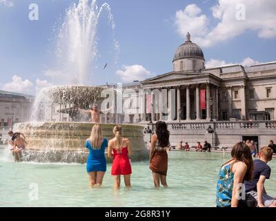 Während einer Hitzewelle im Juli 2021 stehen Menschen in den Springbrunnen vor der National Gallery am Trafalgar Square London Stockfoto