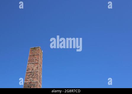 Alter industrieller quadratischer Kamin vor tiefblauem Hintergrund mit Copyspace Stockfoto