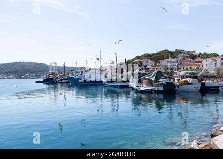 Rogoznica, Kroatien-06.Juli 2021: Möwen fliegen um Fischerboote mit frischem Fang im Hafen von Rogoznica, beliebtes Touristenziel in Stockfoto