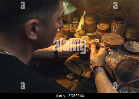 Ein Juwelier repariert in seiner Werkstatt einen goldenen Ring mit einem Stein Stockfoto