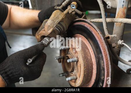 Ein Automechaniker ersetzt die Bremsbeläge, zieht eine Schraube in einen Bremssattel ein Stockfoto