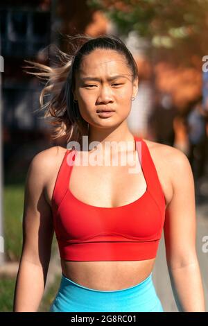 Junge chinesische Frau in Sportkleidung, die Kamera anschaut und im Park posiert. Stockfoto