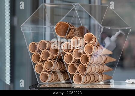 Eiswaffeln in einem transparenten Behälter, der auf der Theke in der Eisdiele steht. Ein kaltes Dessert an einem heißen Tag. Stockfoto