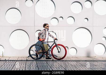 Selbstbewusster Mann mit langem Bart, der mit seinem coolen Fahrrad auf der Straße unterwegs ist. Stockfoto