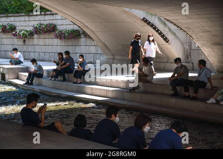 Seoul, Südkorea. Juli 2021. Um den Cheonggyecheon Stream in Seoul herum sitzen Menschen, die Gesichtsmasken tragen, als vorbeugende Maßnahme gegen die Ausbreitung des Coronavirus. Kredit: SOPA Images Limited/Alamy Live Nachrichten Stockfoto