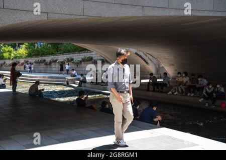 Seoul, Südkorea. Juli 2021. Um den Cheonggyecheon Stream in Seoul herum sitzen Menschen, die Gesichtsmasken tragen, als vorbeugende Maßnahme gegen die Ausbreitung des Coronavirus. Kredit: SOPA Images Limited/Alamy Live Nachrichten Stockfoto