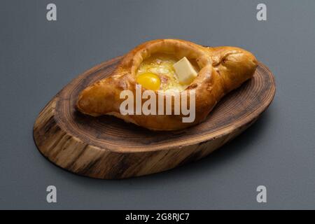 Adjarian khachapuri mit Käse und Eigelb auf Holzbrett auf grauem Hintergrund Stockfoto