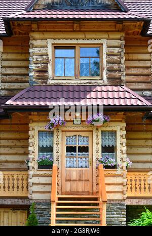 Ein schönes typisches Holzhaus in der kleinen Stadt Zdiar, in der Nähe der Hohen Tatra, Slowakei. Bild aus öffentlichem Boden. Vordertür und Fenster. Stockfoto