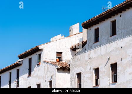 Traditionelle Häuser in der Stadt Chinchon. Alte, verwitterte weiße Fassaden des Wohngebäudes mit blauem Himmel Stockfoto
