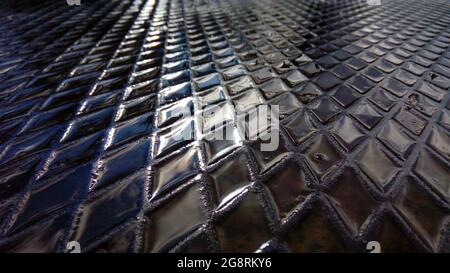 Wasser in den Zellen einer strukturierten Metallplatte. Die Straßen der modernen Stadt nach dem Regen. Das Konzept des Umweltschutzes in modernen Städten. Stockfoto