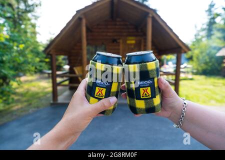 Montana, USA - 2. Juli 2021: Zwei Camper auf einem KOA (Kampgrounds of America) nutzen Koozies oder können gemütlich auf einen lustigen Sommerurlaub anstoßen Stockfoto