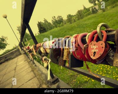Brücke der Liebe mit mehrfarbigen Vorhängeschlössern des Brautpacks. Vorhängeschlösser mit Schlüsseln in den Fluss geworfen, als Symbol für unzerbrechliche Treue und ewig Stockfoto