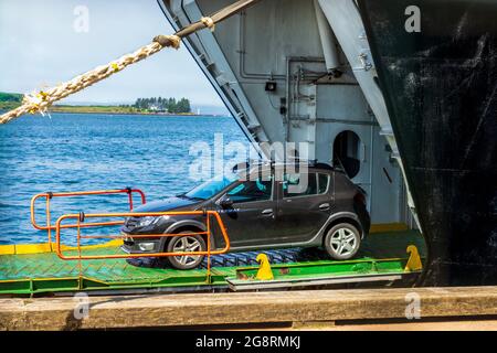 Kleinwagen vor der MV Isle vor Skye, Passagier- und Autofähre im Besitz von Caledonian MacBrayne, wenn sie am Oban Pier, Argyll, Schottland, Großbritannien, anlegen Stockfoto