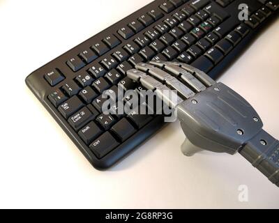 Hand eines Roboters, der auf einer pc-Tastatur arbeitet. Stockfoto