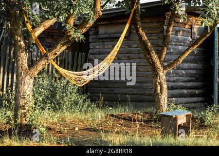 Ländliche Landschaft in Form von Bäumen mit einer Hängematte und einer Scheune. Stockfoto