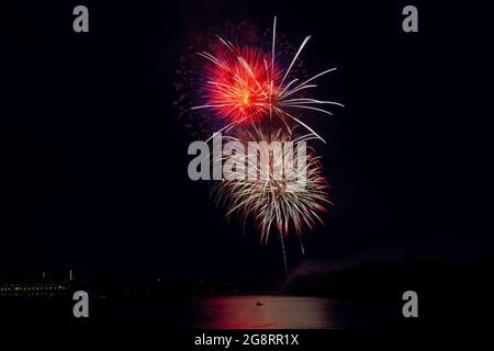 Feuerwerk über dem Fluss in einer großen Stadt. Feierliches Feuerwerk. Stockfoto