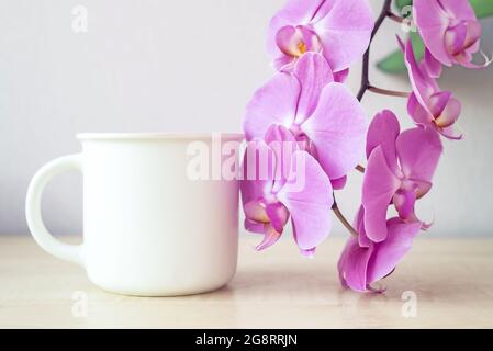 Weißer Kaffeetasse Mockup mit Blumen Flieder Orchidee Nahaufnahme Stockfoto