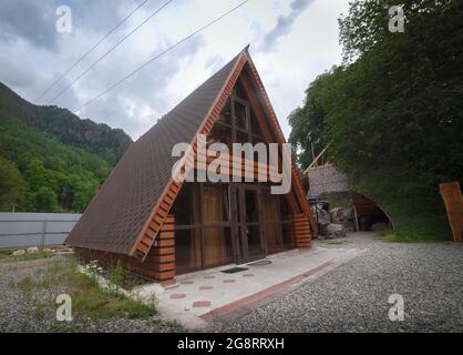 Teberda, Russland 09,07,2021.dreieckiges Holzhaus in den Bergen vor dem Hintergrund des bewölkten Himmels Stockfoto