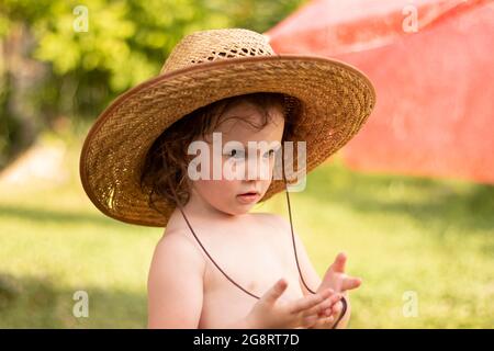 Kleine nachdenkliche Kind in Stroh Cowboy Hut auf verschwommenem Ranch Hintergrund Stockfoto