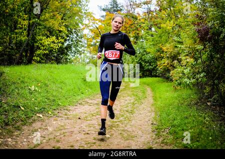 Mädchen konkurriert im Langlauf läuft über einen Weg im Wald. Stockfoto