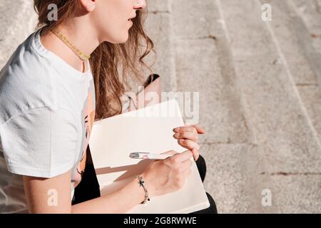 Kaukasische Frau, die im Freien auf einer Treppe sitzt. Konzept der Bildung Stockfoto