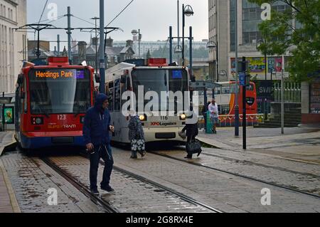 SHEFFIELD. SOUTH YORKSHIRE. ENGLAND. 07-10-21. FitzAlan Square Straßenbahnhaltestelle im Stadtzentrum, zwei Straßenbahnen, die im Regen vorbeifahren. Stockfoto