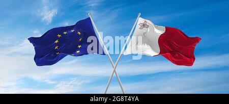 Flaggen der Europäischen Union und Maltas winken im Wind auf Fahnenmasten gegen den Himmel mit Wolken am sonnigen Tag. Symbolisieren Beziehung, Dialog zwischen zwei c Stockfoto