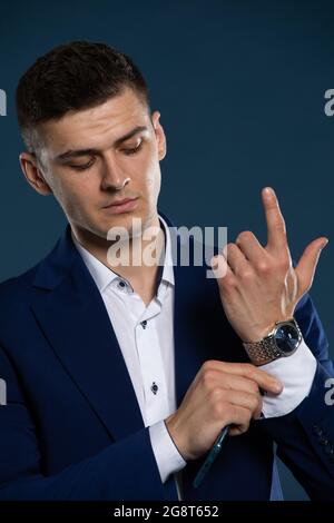Ein Geschäftsmann korrigiert die Manschette seines Hemdes vor einem Treffen. Ein Mann in einem Anzug. Stockfoto