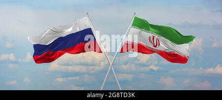 Flaggen Russlands und des Iran winken im Wind auf Fahnenmasten gegen den Himmel mit Wolken am sonnigen Tag. Ein Symbol für die Beziehung, den Dialog zwischen zwei Ländern. Stockfoto