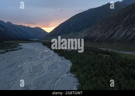 Fluss und Berge bei Sonnenuntergang. Gedreht in Xinjiang, China. Stockfoto
