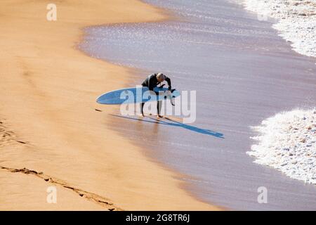 Australischer Surfer mittleren Alters an einem Strand in Sydney passt sein Surfbrett an, Sydney, Australien Stockfoto