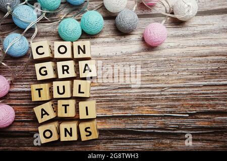 Herzlichen Glückwunsch Buchstaben mit LED-Baumwollkugel Dekoration auf hölzernem Hintergrund Stockfoto