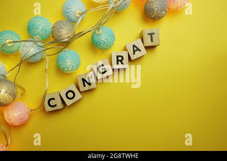 Congrat Alphabet Letter mit LED-Baumwollkugel Dekoration auf gelbem Hintergrund Stockfoto