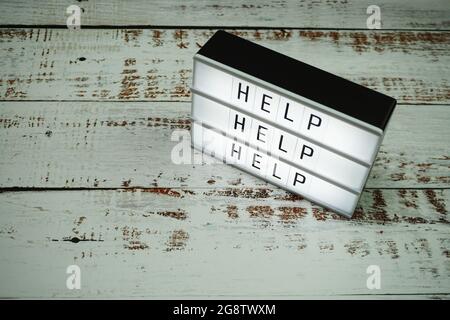 Hilfewort Text in Lichtbox auf hölzernem Hintergrund Stockfoto