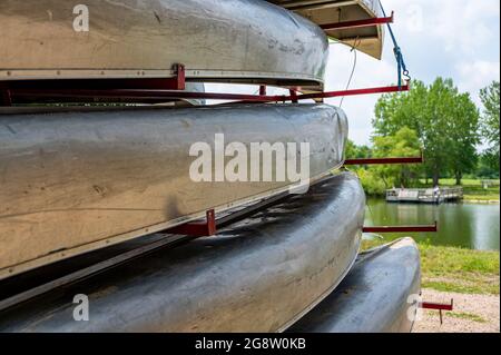 Aluminium-Kanus auf einem Anhänger mit einer Strandfront und offenem Wasser im Hintergrund gestapelt Stockfoto