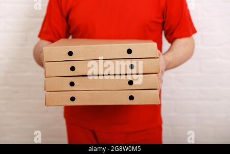 Pizzalieferer, Junge, der Kisten hält. Schnellste Pizzalieferung in der Stadt Stockfoto