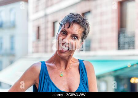 Porträt einer lustigen, kurzen, reifen Frau auf der Straße, die lustige Gesichter macht Stockfoto