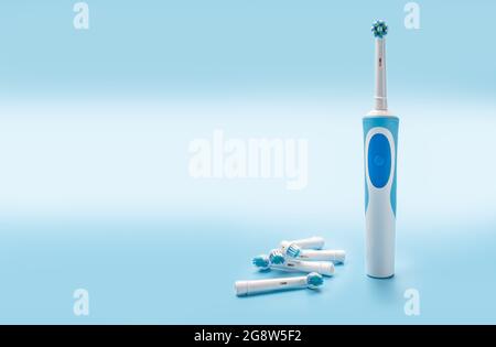 Moderne elektrische Zahnbürste und Ersatzköpfe auf blauem Hintergrund. Modernes Set mit Schallzahnbürsten oder elektrischen Zahnbürsten mit Ersatzköpfen. Platz zum Kopieren Stockfoto