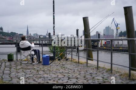 Hamburg, Deutschland. Juli 2021. Ein Angler sitzt im Hafen am Fischmarkt. Kredit: Marcus Brandt/dpa/Alamy Live Nachrichten Stockfoto