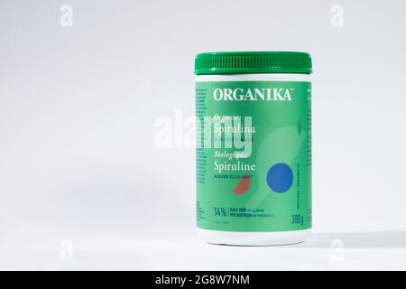 Spirulina-Pulver aus kontrolliert biologischem Anbau befindet sich in einem versiegelten Verpackungsbehälter. Spirulina Pulver der Marke Organika auf weißem Hintergrund isoliert. Stockfoto