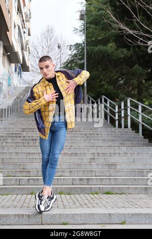 Junge nicht-binäre Person, die auf der Straße tanzt. Stellen Sie eine androgyne Person zusammen. Stockfoto