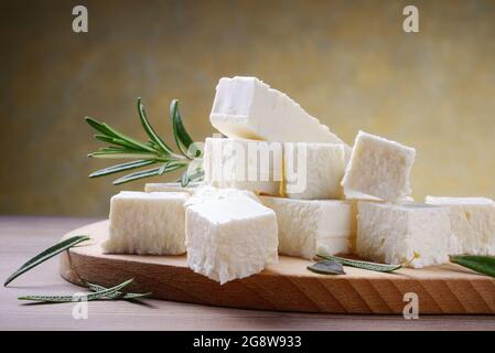 Fetakäse mit Rosmarin auf Holzschneidebrett, selektiver Fokus, Platz für Text, Nahaufnahme. Stockfoto