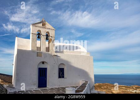 Kirche orthodoxe, kleine weiß getünchte alte Kapelle, kletterte auf felsigen Berg bei Serifos Insel über Chora, Kykladen Griechenland. Ruhiges Ägäisches Meer und blau bewölkt Stockfoto