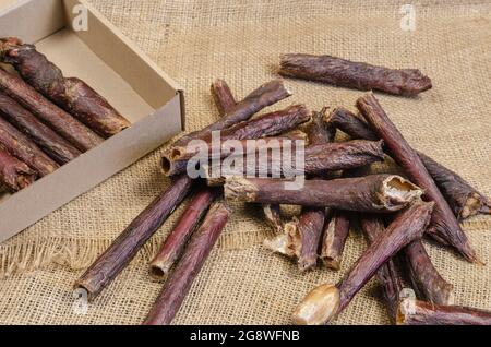 PET Treat und Karton-Box auf Sackleinen-Qualität. Getrocknete Hundeartikel. Köstliche Gullet Sticks Mit Rotem Rindfleisch. Rinderösophagus. Selektiver Fokus Stockfoto